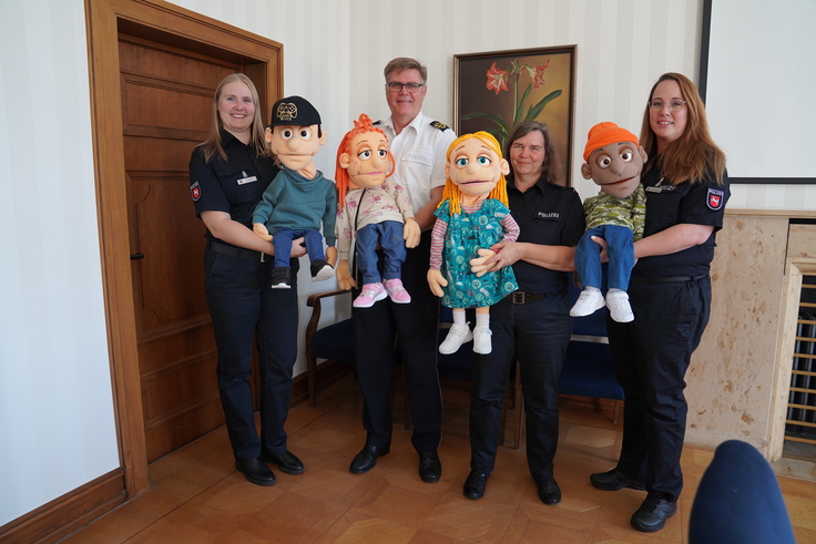 Das Foto zeigt Polizeipräsident Andreas Sagehorn mit den Mitarbeiterinnen der Pädagogischen Puppenbühne und deren Handpuppen