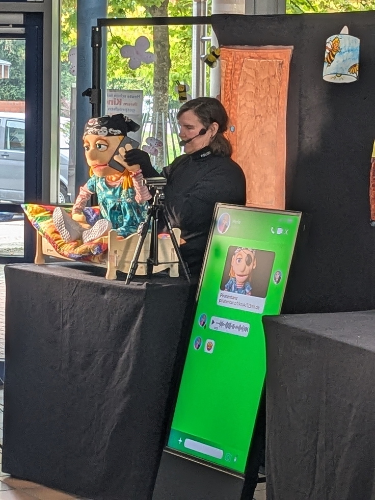 Das Foto zeigt eine Puppenspielerin, die sich ein Mobiltelefon ans Ohr hält
