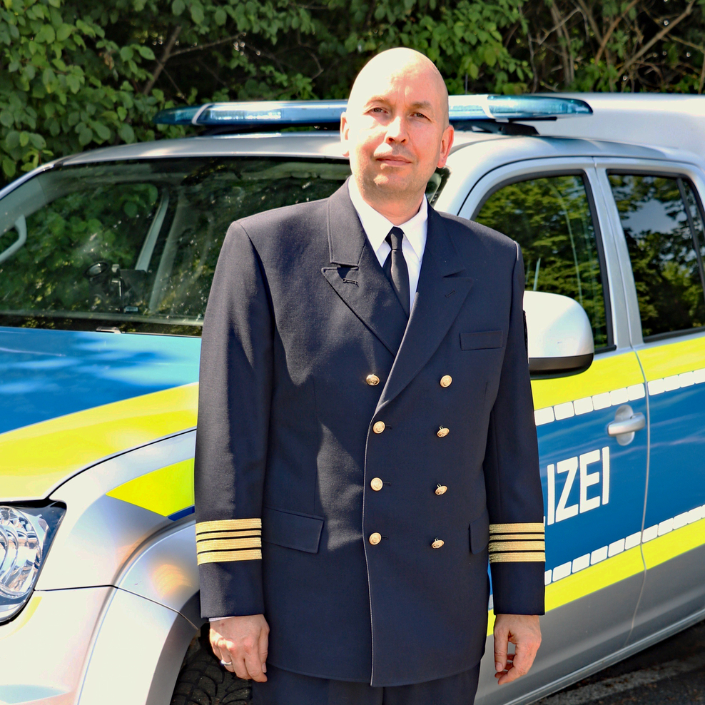 Das Foto zeigt Kriminaloberrat Markus Scharf vor einem Streifenwagen